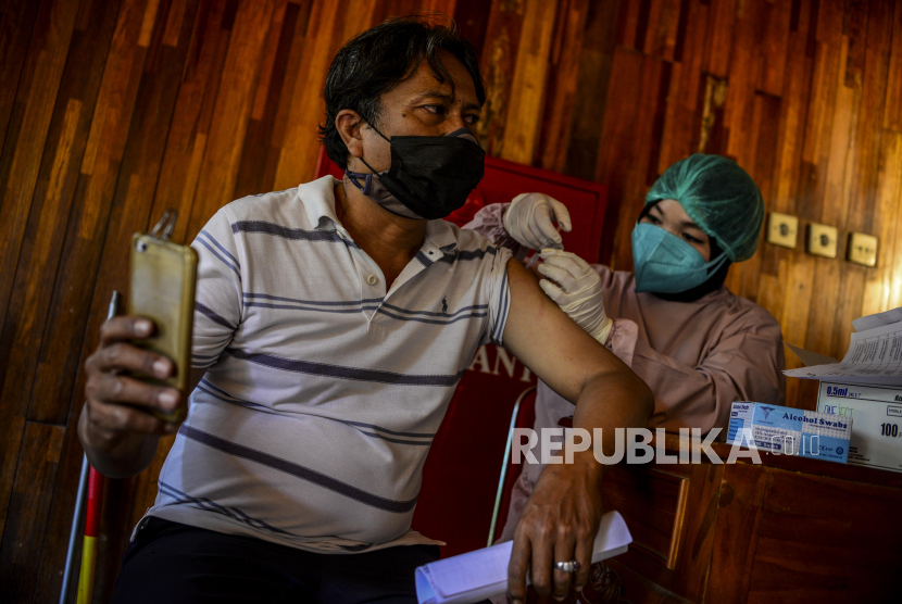 Warga melakukan swafoto saat disuntik vaksin Covid-19 di Kampung Budaya Betawi Setu Babakan, Jagakarsa, Jakarta, Ahad (18/7). Kegiatan serbuan vaksinasi dengan kuota 1.000 orang itu untuk mempercepat program vaksin bagi rakyat Indonesia agar tercipta kekebalan komunal. 