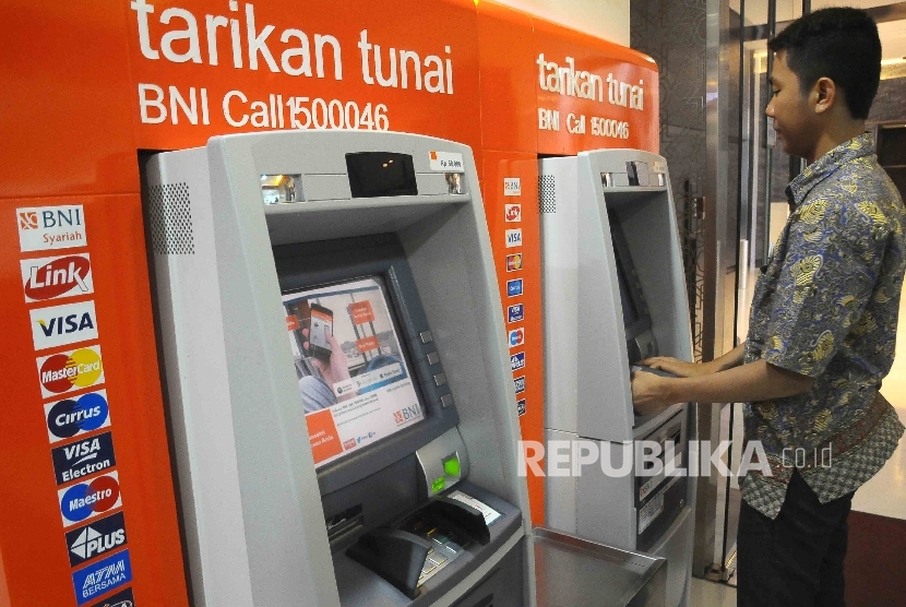  Warga melakukan transaksi menggunakan mesin ATM Bank BNI.