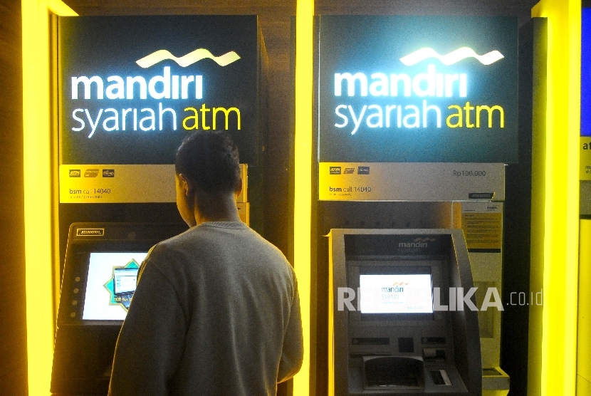 Warga melakukan transaksi menggunakan mesin ATM Bank Mandiri Syariah, Jakarta, Ahad (12/3).