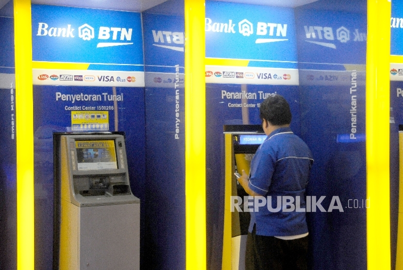 Warga melakukan transaksi menggunakan mesin ATM di bank BTN, Jakarta.