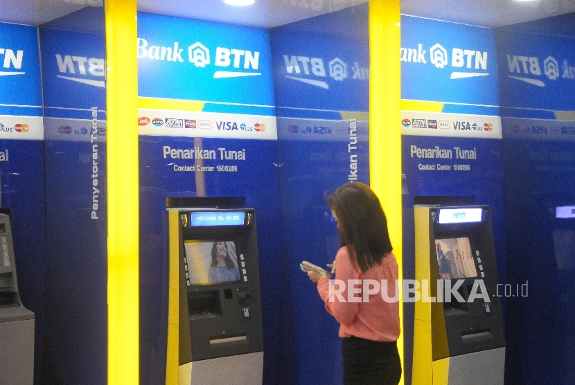 Warga melakukan transaksi menggunakan mesin ATM di bank BTN, Jakarta, Ahad (5/2). 