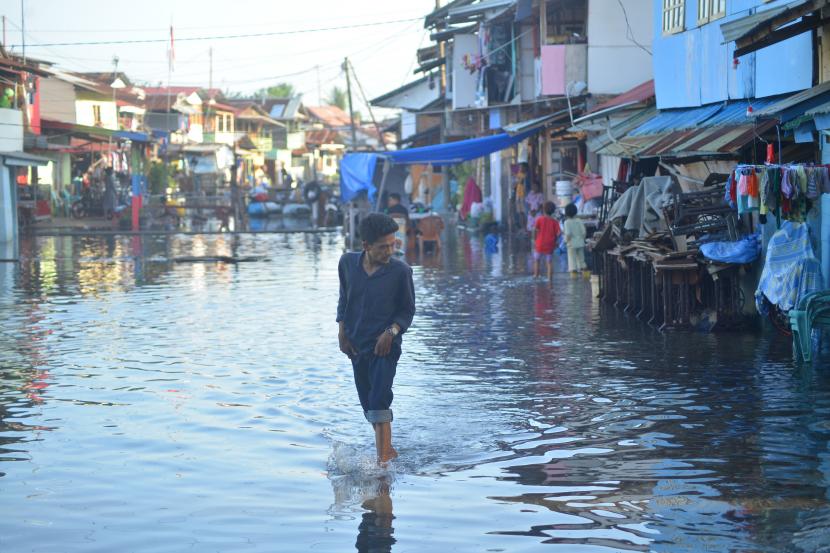 Warga melewati banjir rob yang menggenangi kawasan perkampungan nelayan di Purus Atas, Kota Padang, Sumatera Barat, Rabu (18/5/2022). Banjir rob menggenangi permukiman penduduk di sejumlah titik di kota Padang sejak tiga hari terakhir.