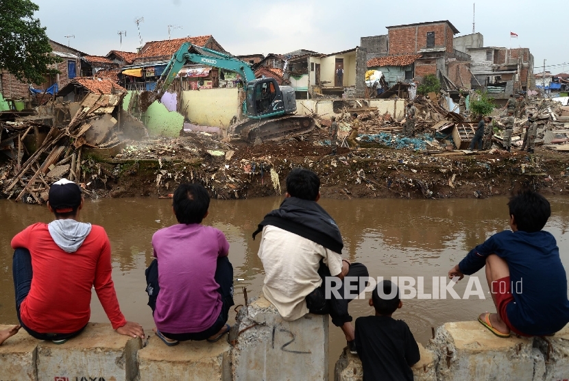 Warga melihat alat berat menghancurkan bangunan tempat tinggal yang berada di pinggiran sungai Ciliwung kawasan Bukit Duri, Jakarta, Selasa (12/1).