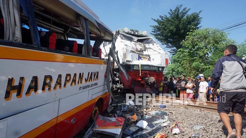 Warga melihat dari dekat kondisi bus dan lokomotif KA Rapih Dhoho yang rusak berat usai tabraka maut di perlintasan kereta api tanpa palang pintu di Desa Ketanon, Tulungagung, Jawa Timur, Ahad (27/2/2022). Kecelakaan yang terjadi sekitar pukul 05.00 WIB itu menyebabkan lima dari 43 penumpang termasuk awak bus meninggal dunia dan 14 lainnya luka-luka dan harus dilarikan ke RSUD dr. Iskak Tulungagung untuk mendapat pertolongan kedaruratan medis.