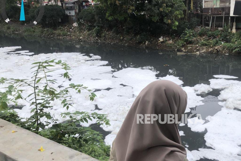 Warga melihat Kali Sunter, Jakarta Utara, yang berbusa akibat pencemaran, Selasa (19/8/2025).
