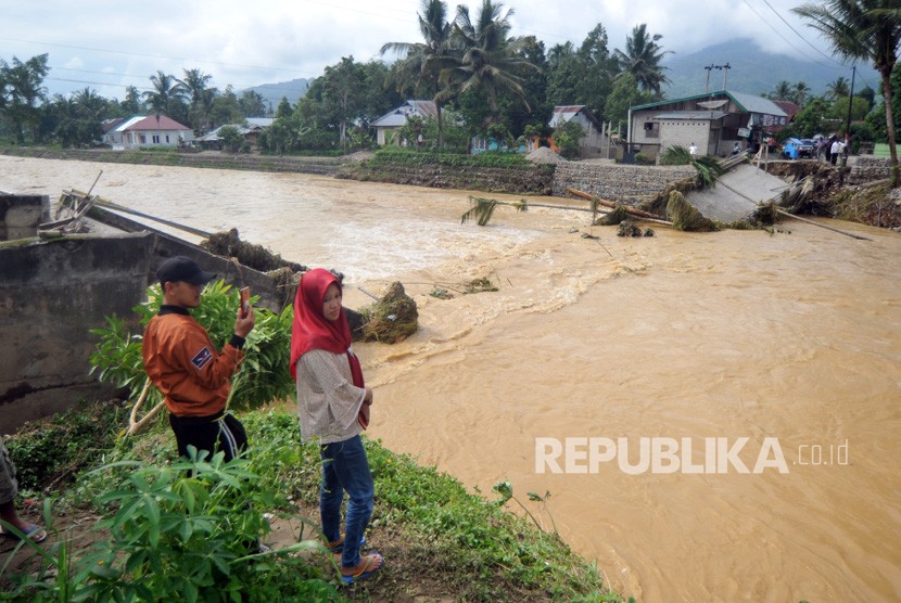  Air bersih, dan bahan pangan, menjadi kebutuhan utama korban banjir di Solok Selatan. foto: Warga melihat kondisi jembatan rusak akibat banjir.