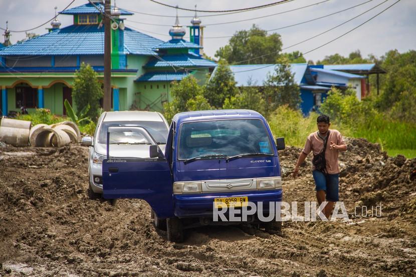 Warga melihat mobilnya yang terjebak di jalan Trans Kalimantan yang rusak di Kecamatan Liang Anggang, Banjarbaru, Kalimantan Selatan, Ahad (19/12/2021). Ruas jalan trans Kalimantan poros selatan yang sedang dalam progres pekerjaan rehabilitasi jalan tersebut rusak parah akibatnya aktivitas warga terganggu. 