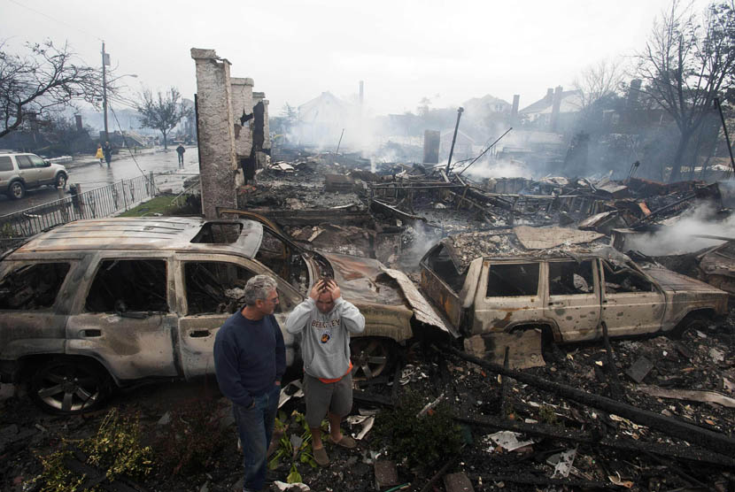 Warga melihat puing rumah yang terbakar akibat Badai Sandy di New York, Selasa (30/10).    (Keith Bedford/Reuters)