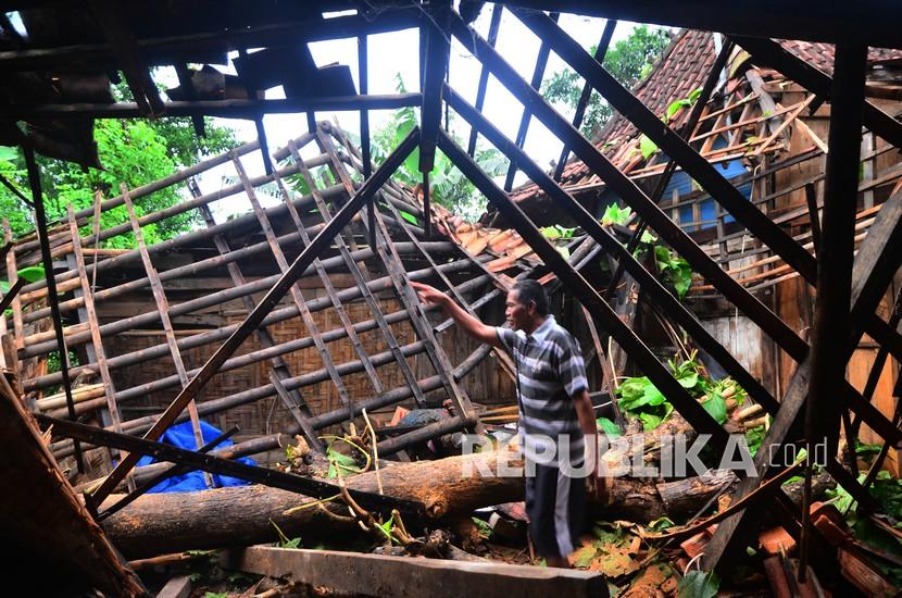 Warga melihat rumah yang rusak tertimpa pohon yang ambruk akibat diterjang angin puting beliung.
