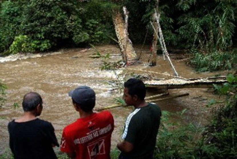 Warga melihat sisa jembatan runtuh di aliran sungai. (Ilustrasi)