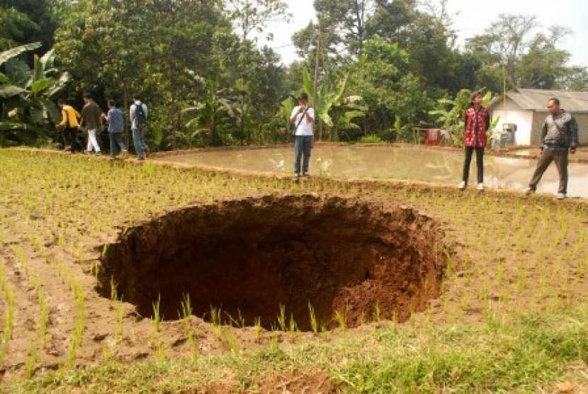 Warga melihat tanah amblas di lahan persawahan Kampung Legoknyenang, Desa Sukamaju, Kecamatan Kadudampit, Sukabumi, Jawa Barat, Jumat (7/9). Di bawah lokasi tanah amblas itu terdapat lintasan aliran air selokan bawah tanah. 