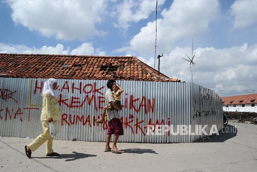   Warga melintas berlatar penolakan pengusuran di kawasan Luar Batang, Penjaringan, Jakarta Utara , Selasa (5/3).(Republika/Tahta Aidilla)