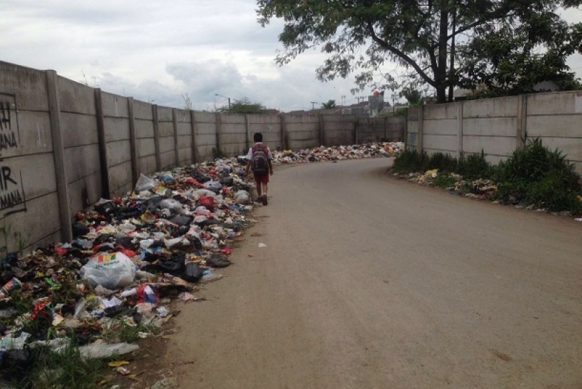 Warga melintas dekat tumpukan sampah di jalur masuk menuju Terminal Baleendah, Bojongsoang, Kabupaten Bandung, Selasa (1/2).