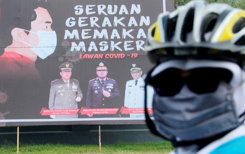 Warga melintas depan spanduk yang bertuliskan Seruan Gerakan Memakai Masker di Jalan Trans Sulawesi, Mamuju, Sulawesi Barat, Selasa (14/4/2020). Pemerintah kota Mamuju memasang himbauan kepada seluruh masyarakat menggunakan masker untuk mengurangi risiko penyebaran wabah virus COVID-19.