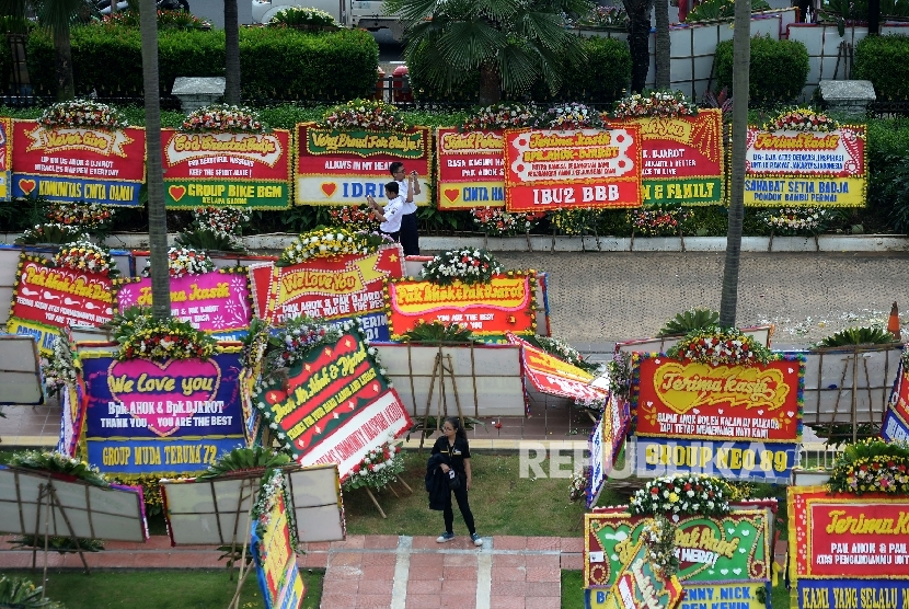 Warga melintas di antara karangan bunga yang ditujukan untuk Gubernur DKI Jakarta Basuki Tjahaja Purnama atau Ahok dan Wakil Gubernur Djarot Saiful Hidayat di halaman kantor Balai Kota Jakarta, Rabu (26/4).