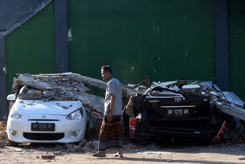 Warga melintas di antara mobil yang rusak akibat gempa bumi (ilustrasi). Ada beberapa hal yang bisa dilakukan pengendara ketika terjadi gempa saat berkendara.