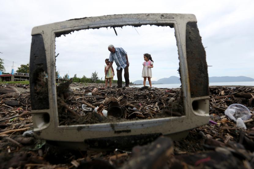 Warga melintas di antara tumpukan sampah laut di pesisir Pantai Gampong Jawa, Banda Aceh, Aceh.