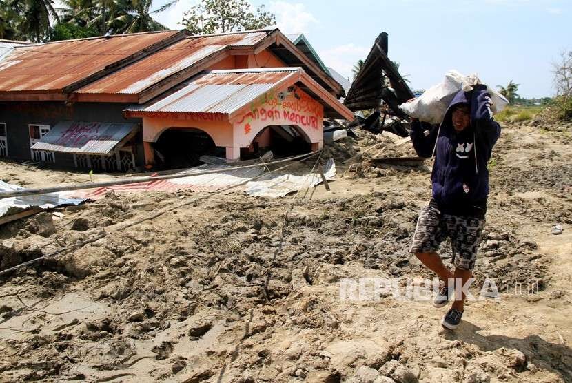 Warga melintas di area lokasi terkena gempa dan lumpur di Desa Sidera, Kabupaten Sigi, Sulawesi Tengah, Selasa (2/10).