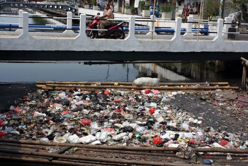 Warga melintas di atas jembatan kali item (Sunter) yang menumpuk banyak sampah, Serdang, Kemayoran, Jakarta, Rabu (16/10).