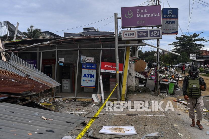 Warga melintas di dekat anjungan tunai mandiri yang rusak akibat gempa bumi magnitudo 6,2 di Mamuju, Sulawesi Barat, Sabtu (16/1/2021). Badan Nasional Penanggulangan Bencana (BNPB) menyatakan korban meninggal dunia akibat gempa di Sulawesi Barat per Sabtu 16 Januari sore sebanyak 46 orang. 