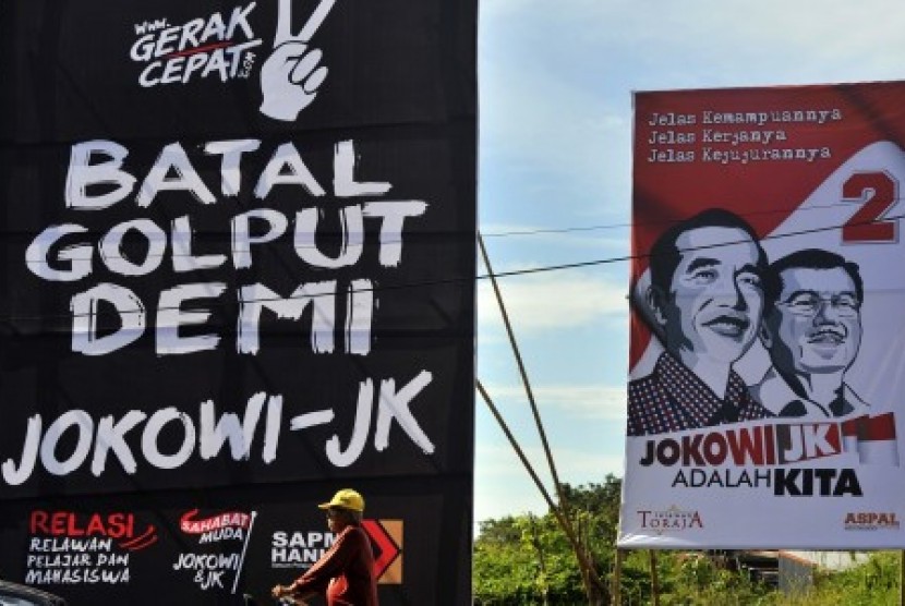 Warga melintas di dekat baliho kampanye anti Golput untuk Capres-Cawapres Joko Widodo-Jusuf Kalla di Makassar, Sulsel, Rabu (25/6). 