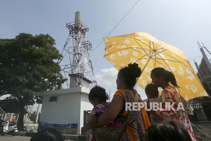 Warga melintas di dekat bangunan sirene sistem peringatan dini 