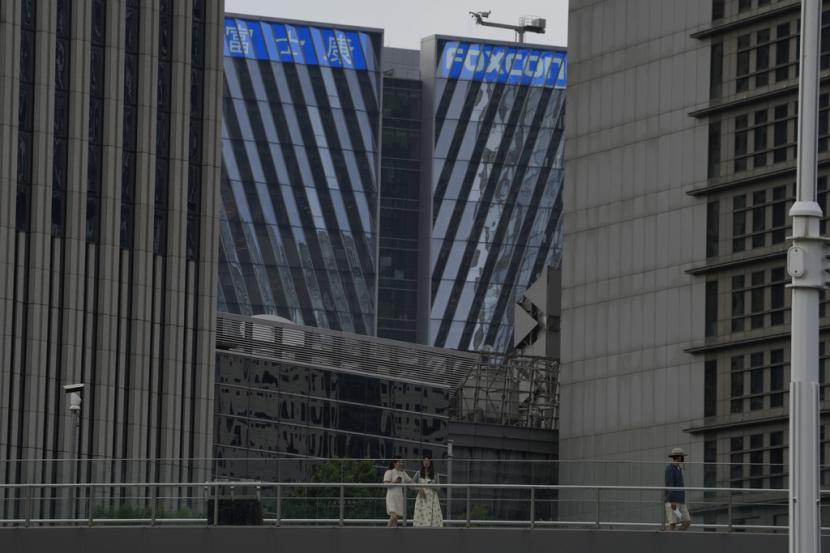Warga melintas di dekat gedung berlogo Foxconn di Shanghai, Selasa, 4 Juli 2023.
