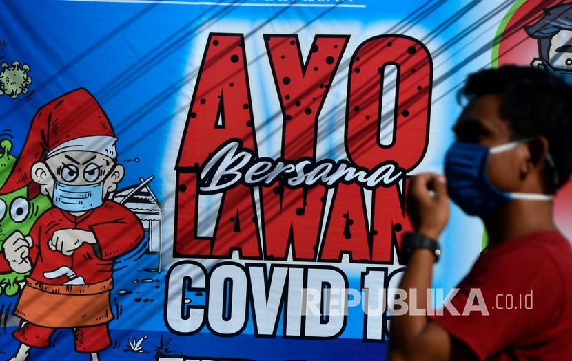 Warga melintas di dekat spanduk bertuliskan Ayo Bersama Lawan COVID-19 di Makassar, Sulawesi Selatan, Kamis (16/4/2020). Menteri Kesehatan menyetujui penerapan Pembatasan Sosial Berskala Besar (PSBB) di Makassar dalam percepatan penanganan COVID-19.
