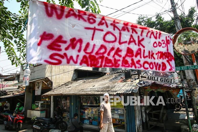 Warga melintas di dekat spanduk peringatan untuk pemudik di kawasan Sawah Besar, Jakarta, Ahad (16/5/2021). Spanduk tersebut untuk memperingati warga yang kembali dari mudik agar membawa surat bebas COVID-19.