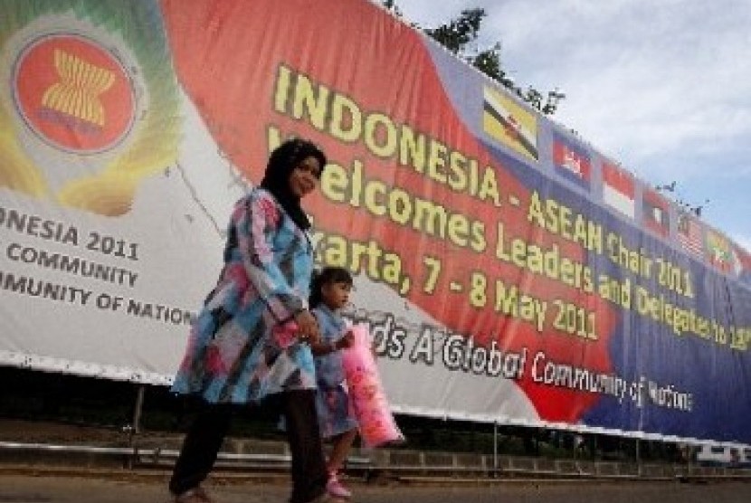 Warga melintas di depan baliho besar bertemakan penyelenggaraan Konferensi Tingkat Tinggi (KTT) ASEAN ke-18.