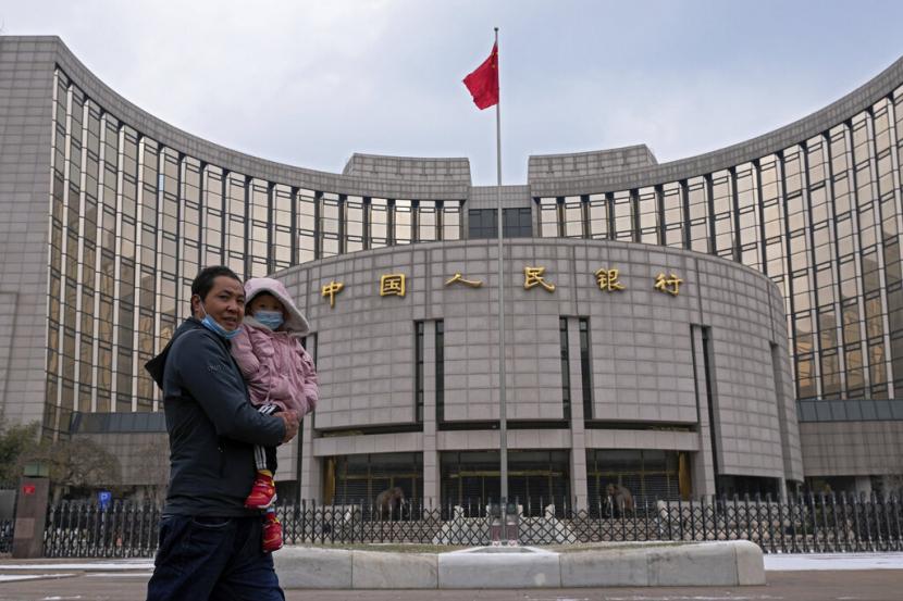 Warga melintas di depan gedung kantor bank sentral China, Peoples Bank of China (PBoC). Dua bank milik negara terbesar di China membatasi pembiayaan untuk pembelian komoditas Rusia menyusul invasi yang dilakukan Rusia ke Ukraina.