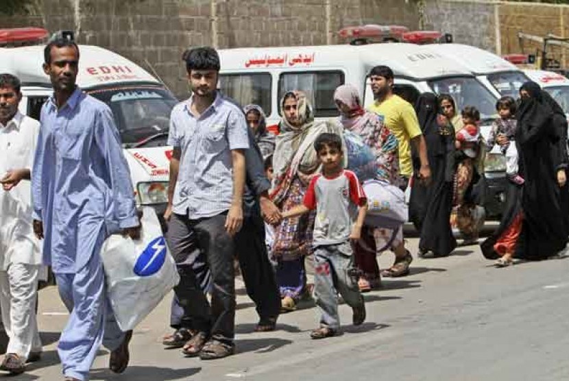 Warga melintas di depan mobil ambulans di kota Lyari, Pakistan, Ahad (29/4). (Ilustrasi)