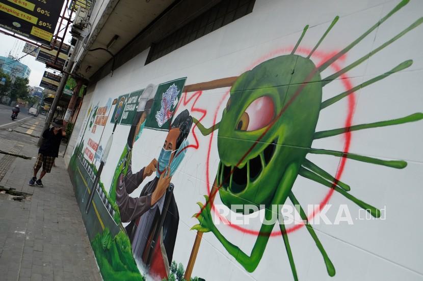 Warga melintas di depan mural bergambar Polwan memasangkan masker yang rusak dicoret di Jalan Stasiun Kereta Api, Medan, Sumatera Utara. Petugas gabungan Satgas COVID-19 menutup sementara pusat jajanan Medan Night Market di Jalan Haji Adam Malik Kota Medan, Provinsi Sumatera Utara karena beroperasi lewat jam batas yang sudah ditentukan.