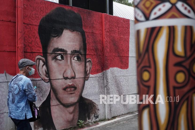 Warga melintas di depan mural bergambar Wali Kota Solo Gibran Rakabuming Raka di Purwosari, Solo, Jawa Tengah. Gibran tak ambil pusing soal pelaporannya ke KPK.