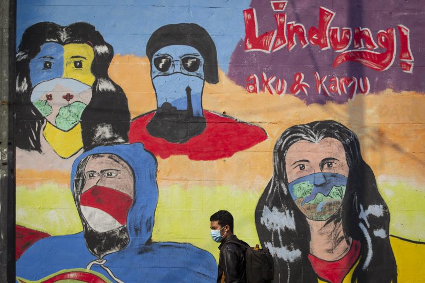 Warga melintas di depan mural berisi pesan ajakan menggunakan masker di kawasan Pancoran, Jakarta. Satgas Penanganan Covid-19, Senin (9/11), mengungkap tingkat positivity rate hari ini dilaporkan 11,52 persen. Angka ini jauh di bawah tingkat positif pada Ahad (8/11) kemarin, 18,52 persen.
