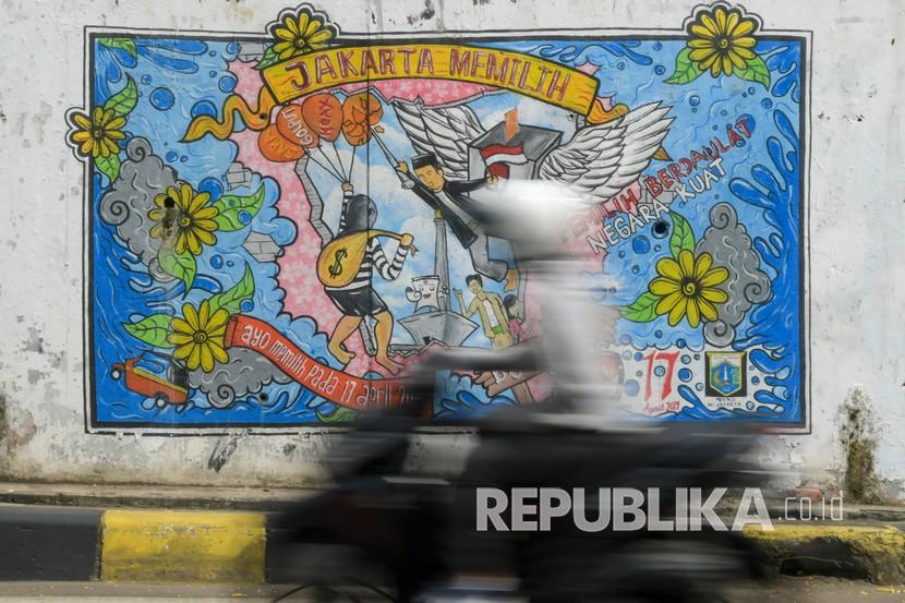 Warga melintas di depan mural bertema pemilihan umum di kawasan Dukuh Atas, Jakarta, Rabu (6/5/2020). Presiden Joko Widodo resmi tunda pelaksanaan Pilkada Serentak 2020 hingga Desember 2020 karena wabah COVID-19. 