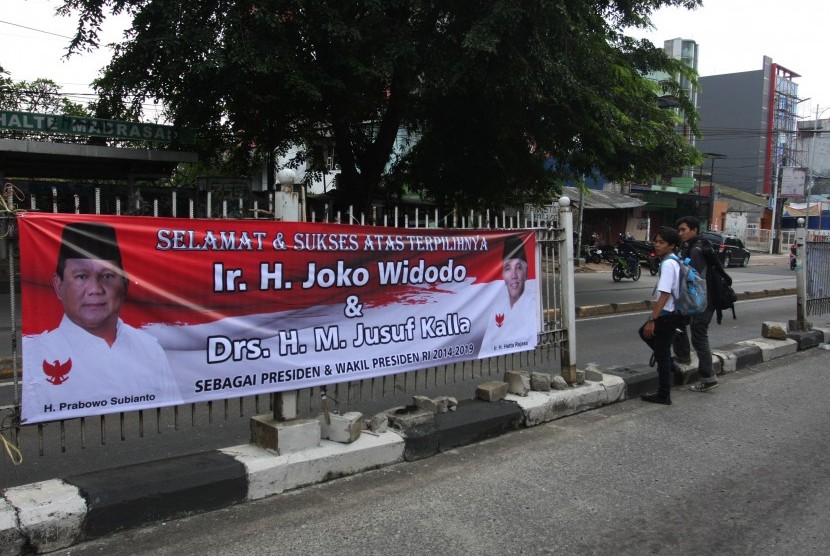 Warga melintas di depan spanduk ucapan selamat atas terpilihnya Jokowi-JK menjadi Presiden RI 2014-2019 dengan gambar Prabowo Subianto dan Hatta Rajasa di Jakarta, Rabu (23/7).