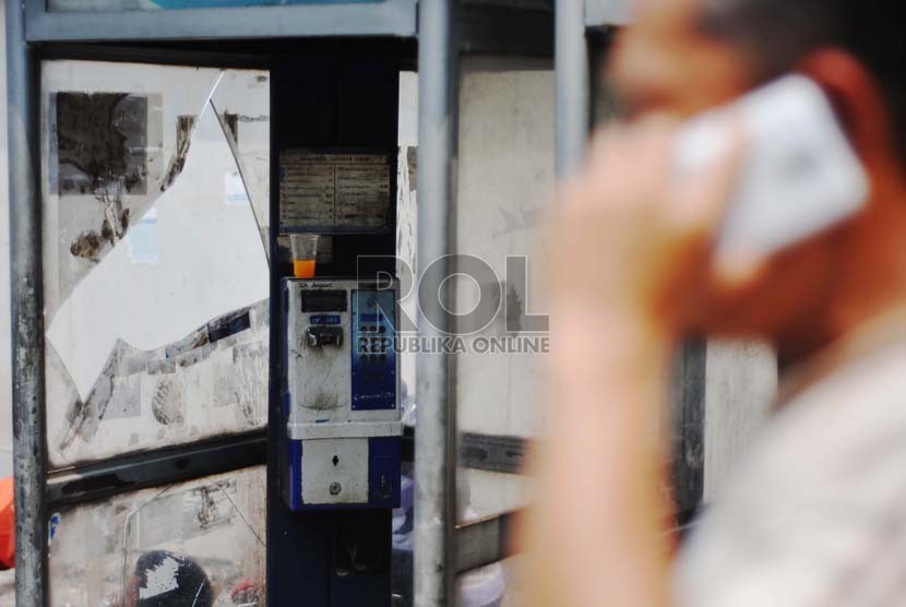 Warga melintas di depan telepon umum koin di kawasan Sudirman, Jakarta Selatan, Senin (13/10).(Republika/Raisan Al Farisi)