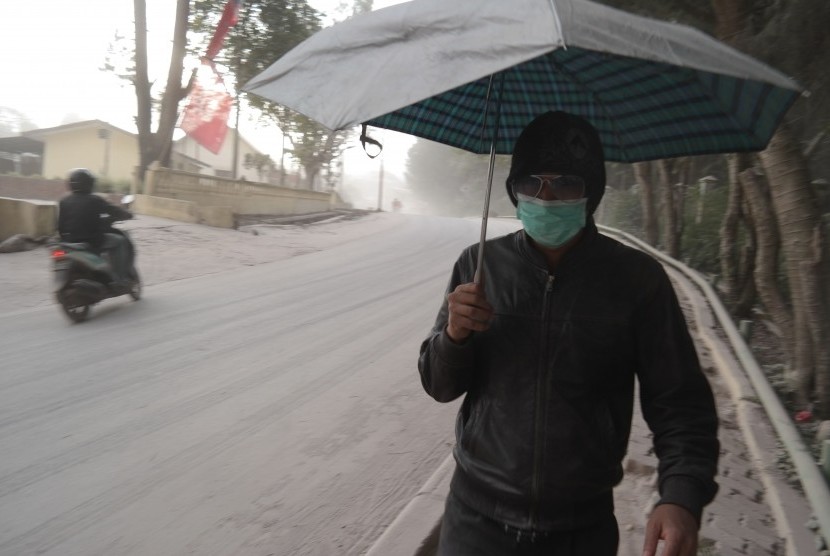   Warga melintas di jalan ketika hujan abu vulkanik erupsi Gunung Sinabung, di Berastagi, Karo, Sumatera Utara, Jumat (26/6).