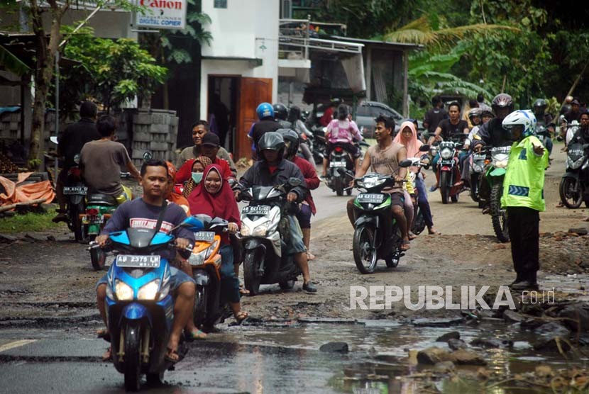 Warga melintas di jalan Sriharjo, Bantul, Yogyakarta yang terkikis akibat banjir. Pemkab Bantul menunggu rekomendasi pakar geologi untuk perbaiki jalan ambles Sriharjo