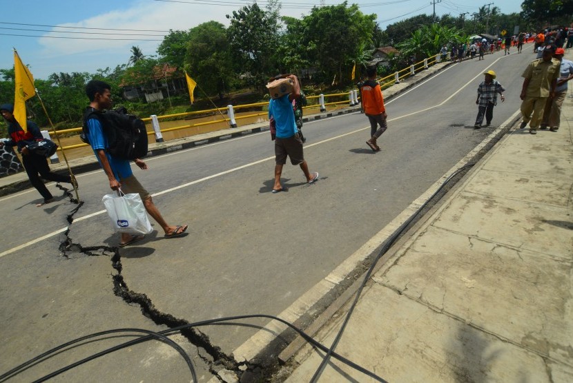 Warga melintas di jalan utama jembatan Putrapinggan, di Kecamatan Kalipucang, Kabupaten Pangandaran, Jawa Barat, Senin (10/10), setelah terjadi bencana longsor. 