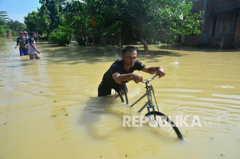 Ilustrasi. Warga melintas di jalan yang tergenang air di Desa Cingrong, Purwodadi, Grobogan, Jawa Tengah, Rabu (16/3/2022). Seorang Warga Meninggal Dunia Terseret Banjir Bandang di Grobogan
