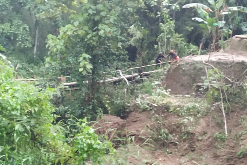 Warga melintas di jembatan darurat yang dibangun menuju wilayah yang terisolasi di dua desa di Kecamatan Cisayong dan Sukaratu, Kabupaten Tasikmalaya, Jumat (28/2) sore.