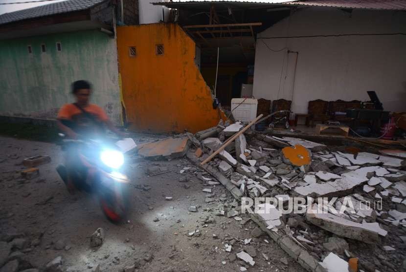Warga melintas di reruntuhan rumah pascagempa di Palu, Sulawesi Tengah, Jumat (28/9). 