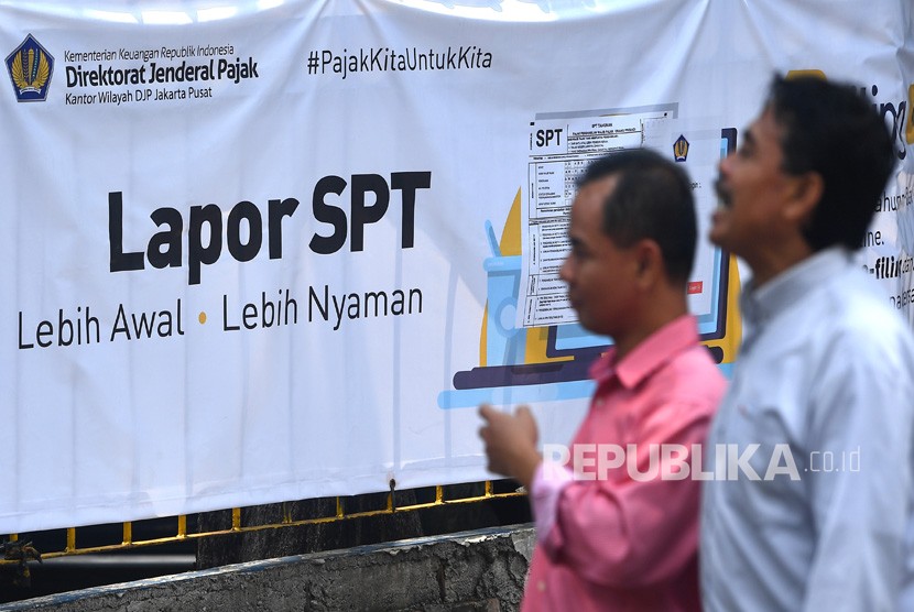 Warga melintas di samping spanduk himbauan pelaporan surat pemberitahuan (SPT) tahunan pajak di KPP Pratama Jakarta Tanah Abang Satu, Jakarta, Senin (19/3). 