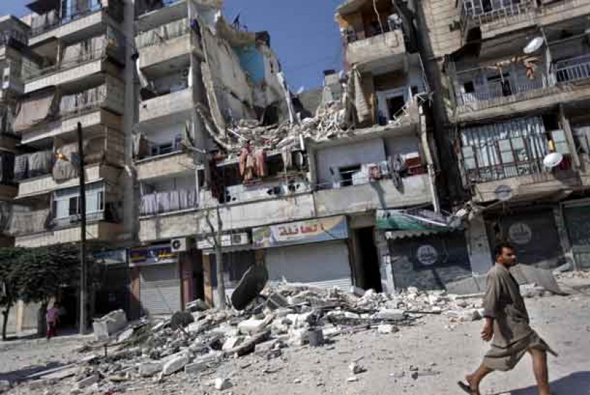  Warga melintas di sebuah bangunan yang hancur oleh serangan udara di Aleppo, Suriah.