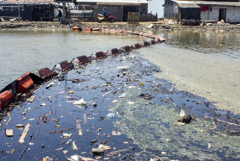 [Ilustrasi] Warga melintas di sekitar tambak ikan yang terdampak tumpahan minyak mentah di Desa Cemarajaya, Cibuaya, Karawang, Jawa Barat, Jumat (30/8/2019).