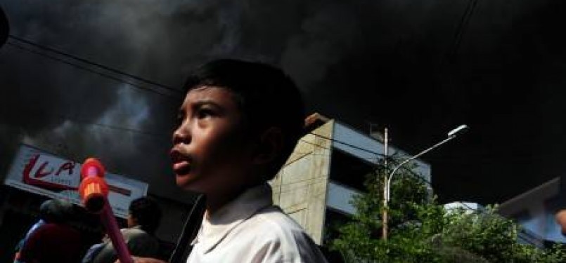 Warga melintas di tengah kebakaran yang melanda pemukiman di Jalan Lautze, kawasan Kartini, Jakarta Pusat, Selasa (7/2). 