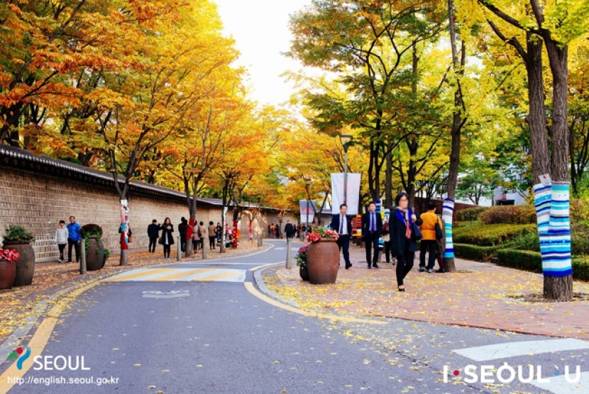 Warga melintas di trotoar saat musim gugur di Kota Seoul.