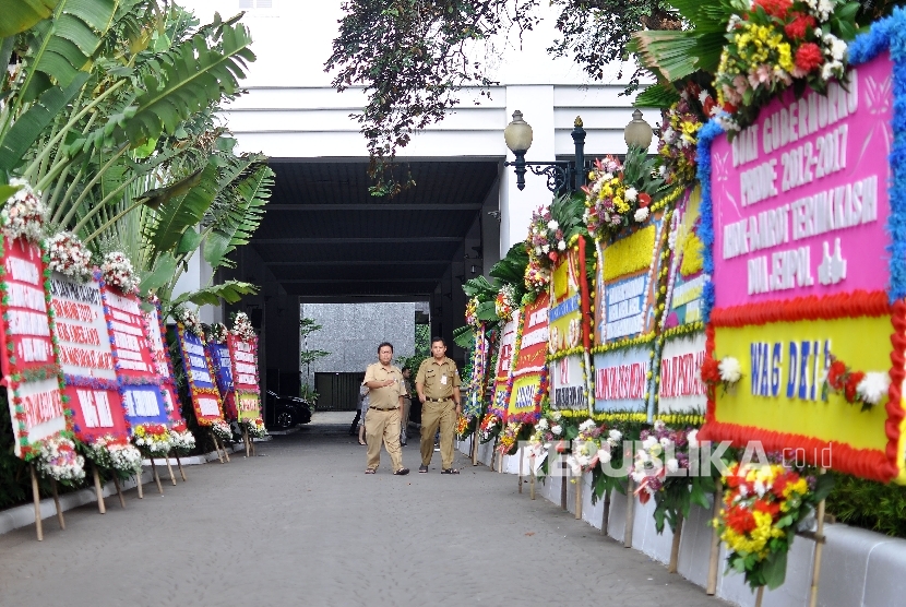 Warga melintas diantara karang bunga yang berisi ucapan terima kasih kepada Basuki Tjahaya Purnama dan Djarot Saiful Hidayat di Balai Kota DKI Jakarta, Senin (9/10).